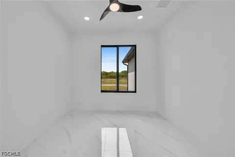 an empty room with windows and fan
