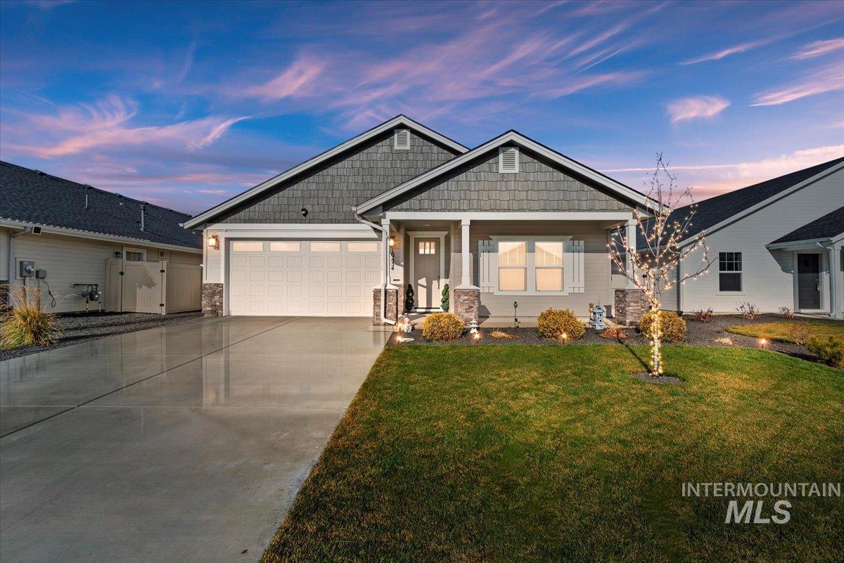 Craftsman house with driveway, a yard, a garage, covered porch, and stone siding