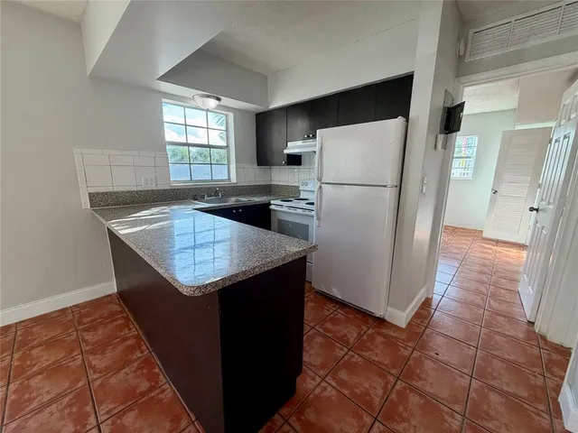 a kitchen with granite countertop a refrigerator and a sink