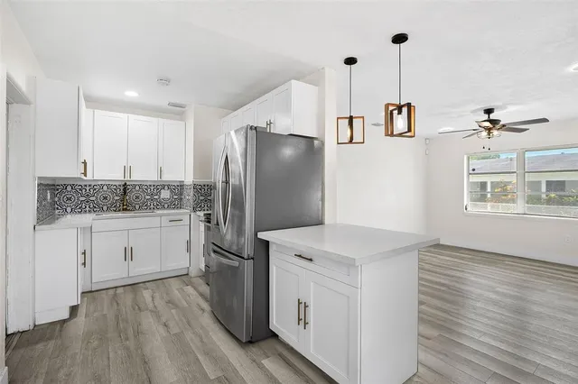 a kitchen with a refrigerator and white cabinets