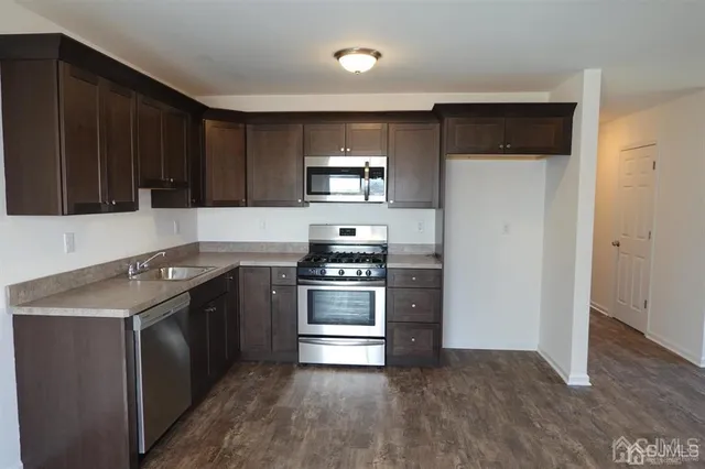 a kitchen with stainless steel appliances granite countertop a stove a refrigerator and a sink with wooden floor