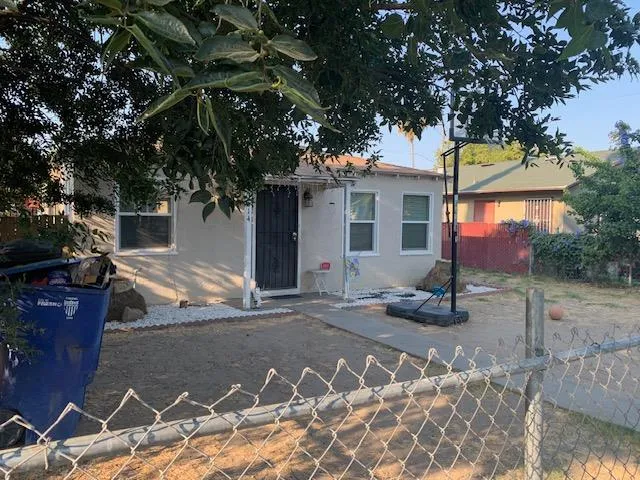 a view of a white house with a large tree