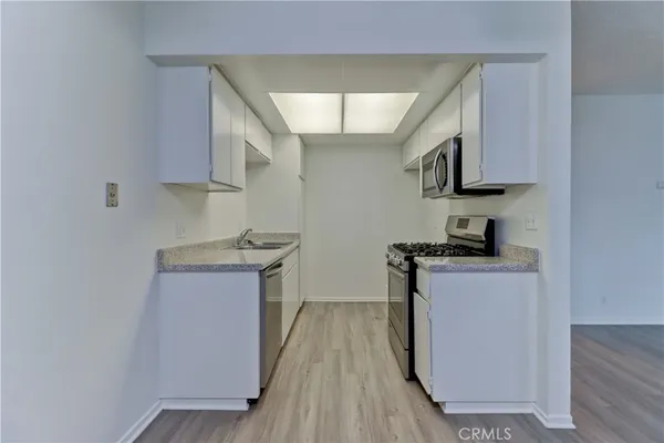 a kitchen with stainless steel appliances a sink stove and wooden floor