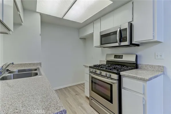 a kitchen with stainless steel appliances granite countertop white cabinets a stove top oven a sink and dishwasher
