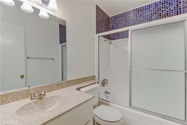 a bathroom with a granite countertop sink toilet and shower
