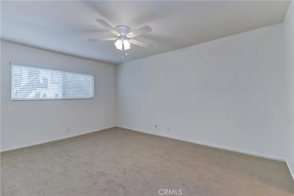 an empty room with windows and fan