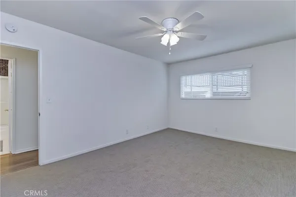 an empty room with a chandelier fan and windows