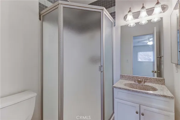 a bathroom with a granite countertop sink a toilet and a mirror