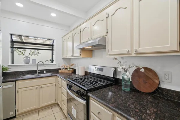a kitchen with stainless steel appliances granite countertop a stove a sink and a white cabinets