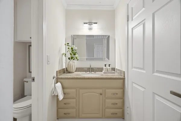 a bathroom with a granite countertop sink vanity mirror and toilet