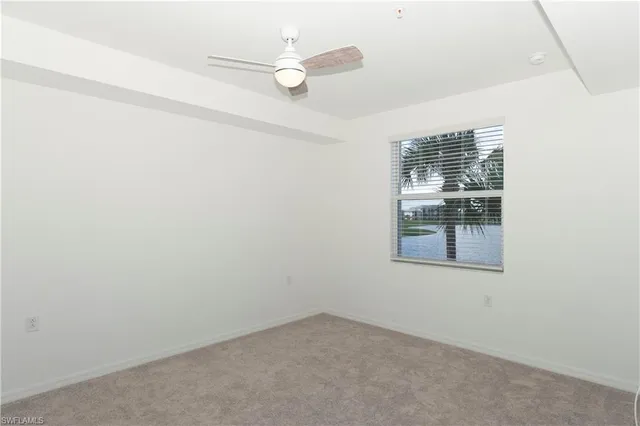 an empty room with a window and ceiling fan