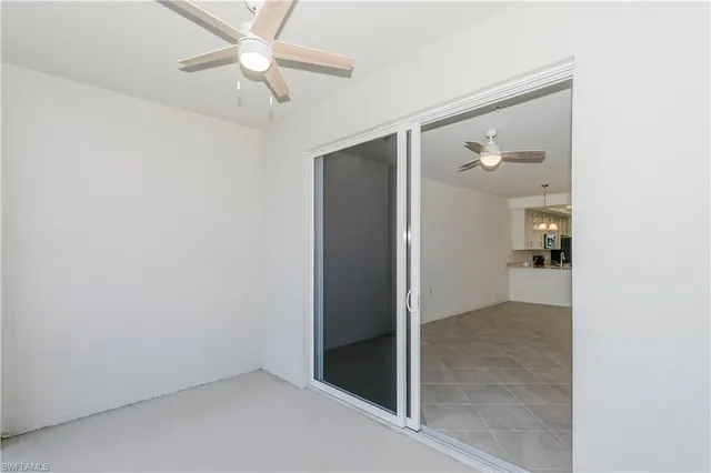 an empty room and chandelier fan in hallway