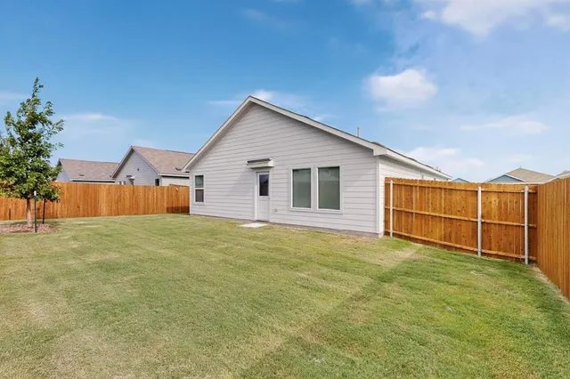 a view of a house with backyard and wooden fence