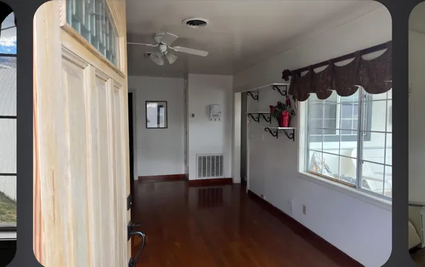 a view of a hallway with wooden floor and windows