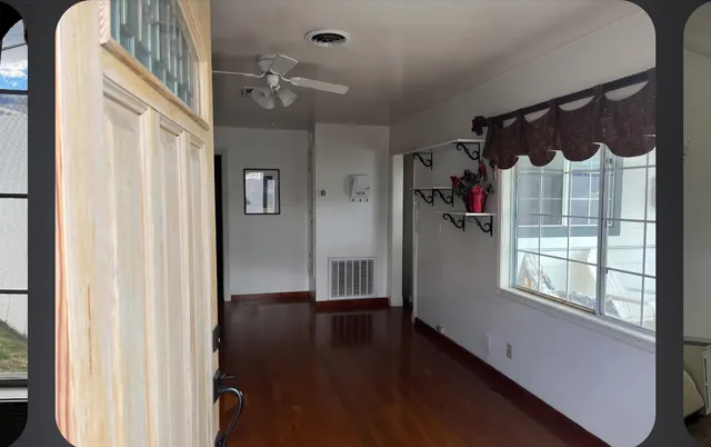 a view of a hallway with wooden floor and windows