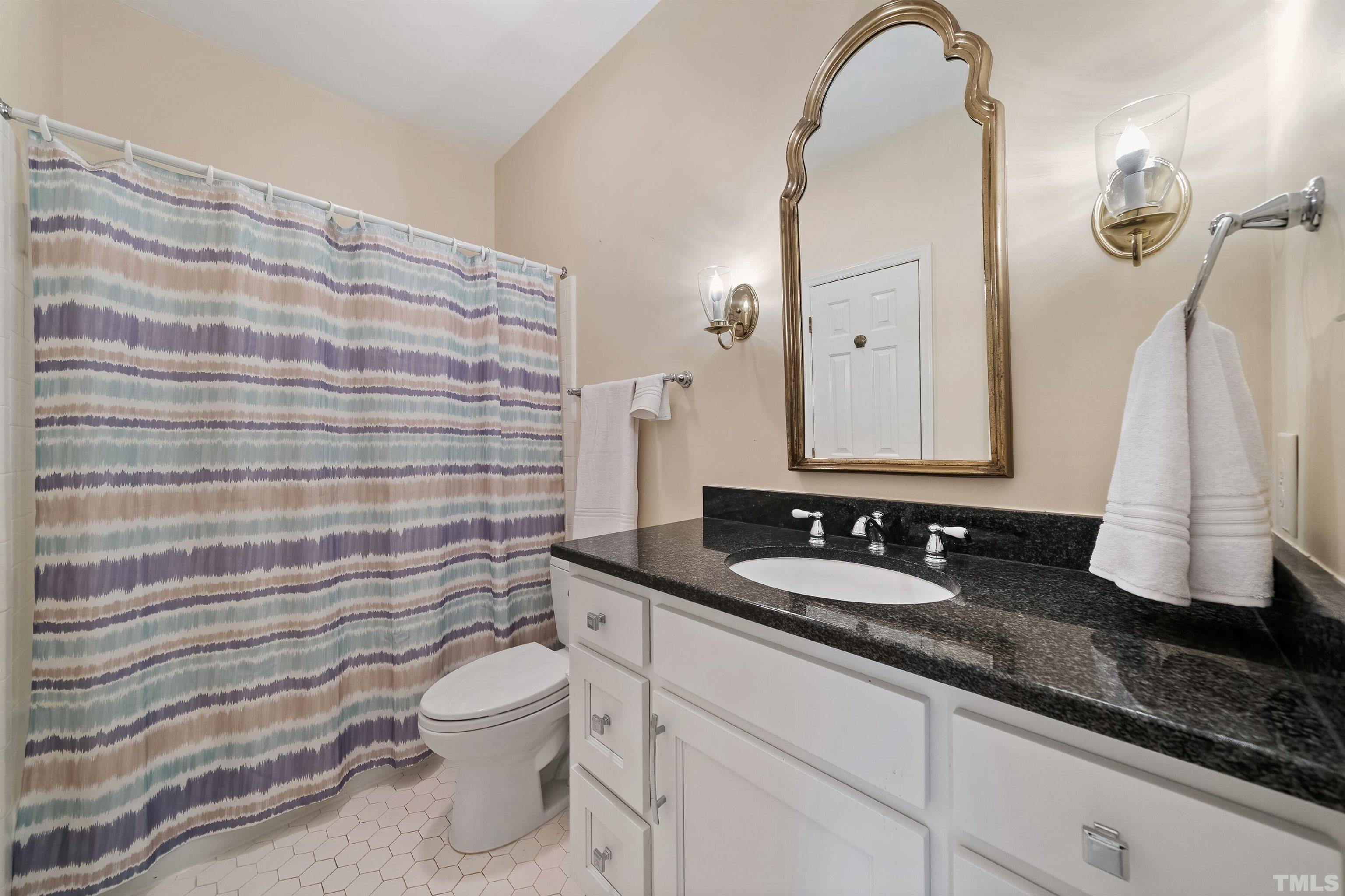 2623 Ashland Street Raleigh, NC 27608 - Photo 14 of 18 a bathroom with a granite countertop sink a toilet and a mirror