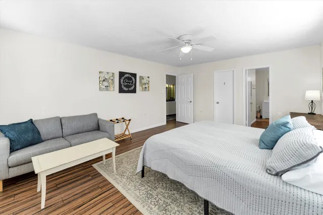 a bedroom with a bed a couch and windows