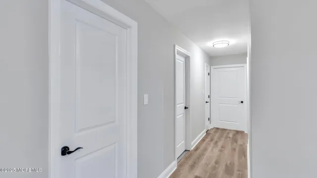a view of a hallway with wooden floor and a bathroom