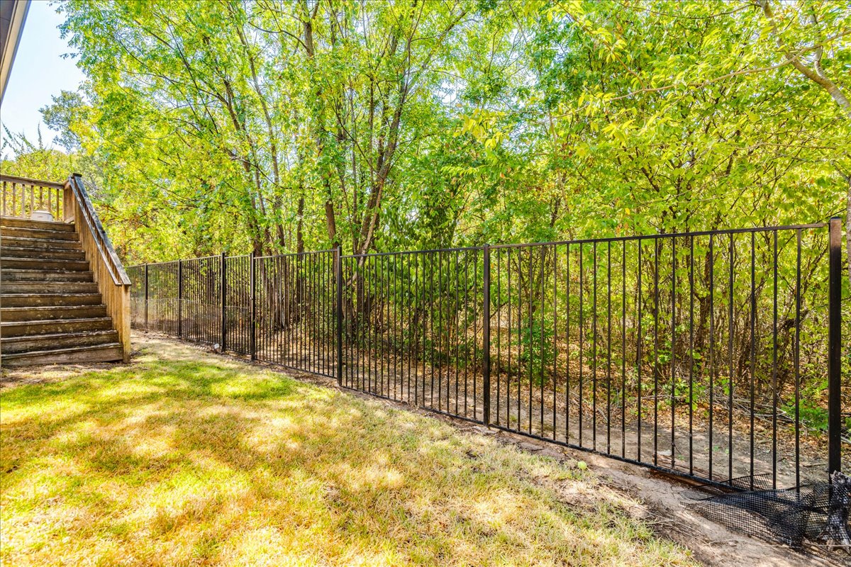 12909 Medina River Way Austin, TX 78732 - Photo 34 of 36 Mature trees border a grassy yard secured by a wrought iron fence that leads you out into the greenbelt.