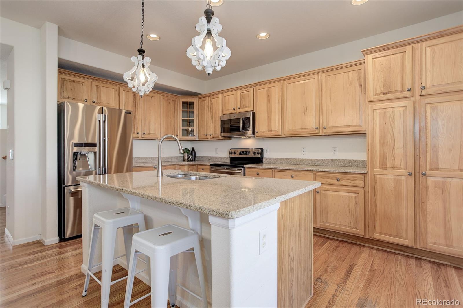 674 Bristle Pine Circle, Unit D Highlands Ranch, CO 80129 - Photo 19 of 31 a kitchen with stainless steel appliances granite countertop a refrigerator a stove a sink dishwasher and white cabinets with wooden floor