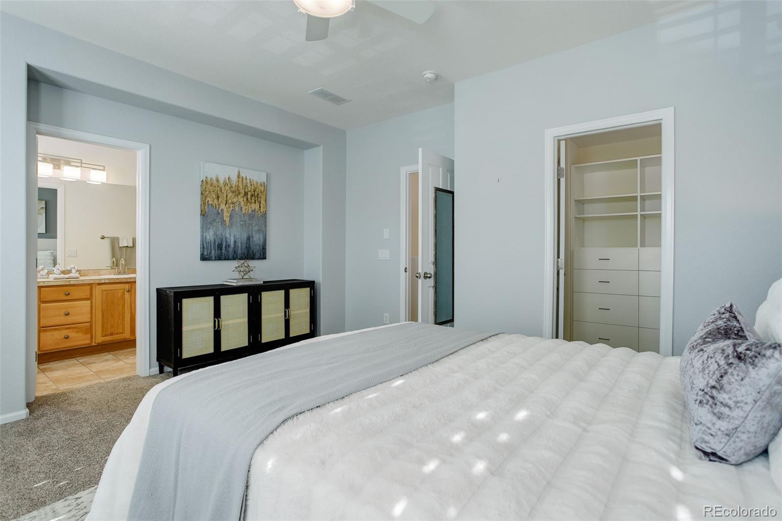 674 Bristle Pine Circle, Unit D Highlands Ranch, CO 80129 - Photo 23 of 31 a bedroom with a bed and a view of en suite bathroom