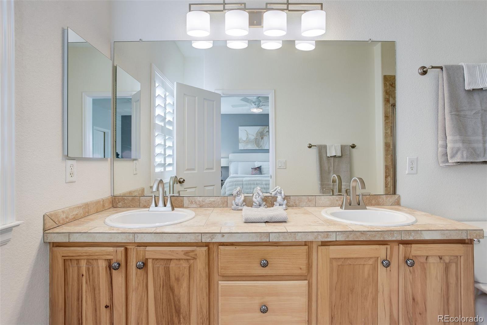 674 Bristle Pine Circle, Unit D Highlands Ranch, CO 80129 - Photo 24 of 31 a bathroom with a granite countertop sink a large mirror and a