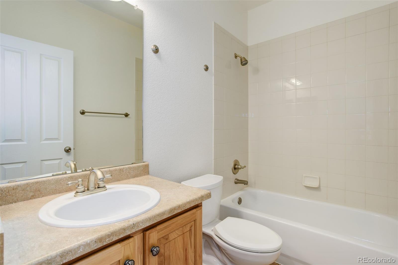 674 Bristle Pine Circle, Unit D Highlands Ranch, CO 80129 - Photo 26 of 31 a bathroom with a granite countertop sink toilet a mirror and shower