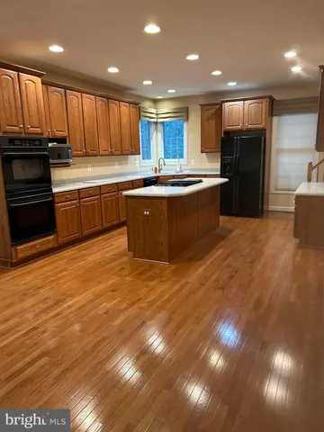 a kitchen with kitchen island granite countertop wooden floors stainless steel appliances a sink and a counter