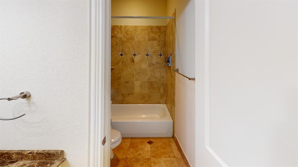 4516 Gilbert Avenue Dallas, TX 75219 - Photo 19 of 28 Full bathroom featuring a tub/shower combination with tile surround, a toilet, and patterned tile flooring