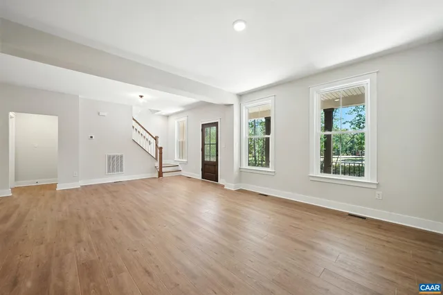 an empty room with windows a fireplace and wooden floor