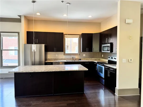 a kitchen with stainless steel appliances granite countertop a refrigerator a sink dishwasher a stove and a large window