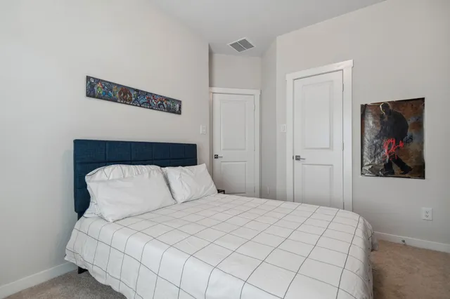 a bedroom with a large bed and a painting on the wall