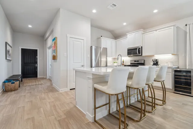 a kitchen with kitchen island granite countertop a stove a sink a refrigerator cabinets and a dining table with wooden floor