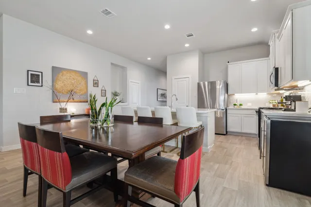 a kitchen with stainless steel appliances a dining table chairs and refrigerator