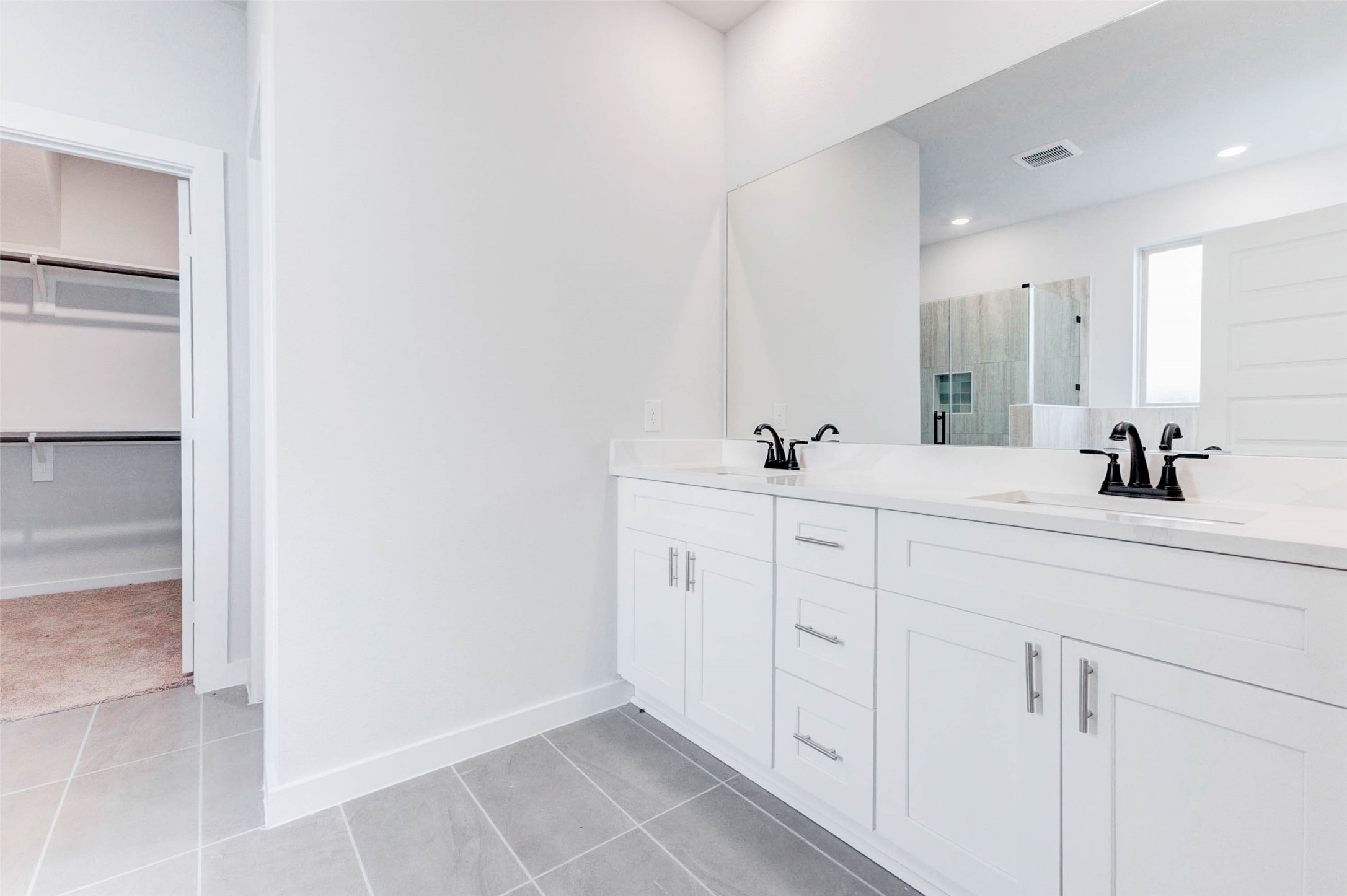 6406 Pomona Court Rosharon, TX 77583 - Photo 20 of 33 The spa-like primary bath features a sleek double-sink vanity with quartz countertops and ample storage. A full-width mirror expands the space visually, while matte black fixtures add a touch of modern elegance to your morning and evening routines.