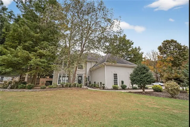 a view of a house with a yard and large tree