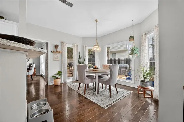 a dining room with wooden floor a chandelier a wooden table and chairs