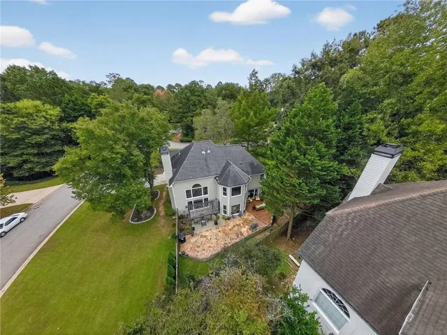 an aerial view of a house with yard and trees in the background