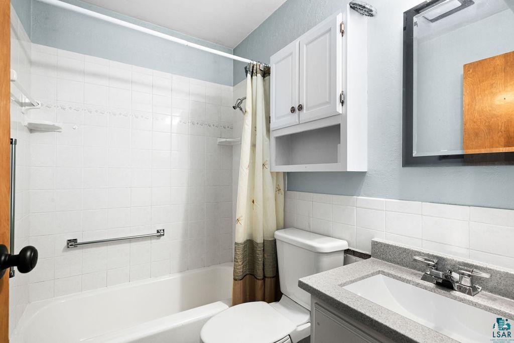 33 Nelson Drive Silver Bay, MN 55614 - Photo 23 of 40 Bathroom with toilet, tile walls, shower / tub combo with curtain, and vanity
