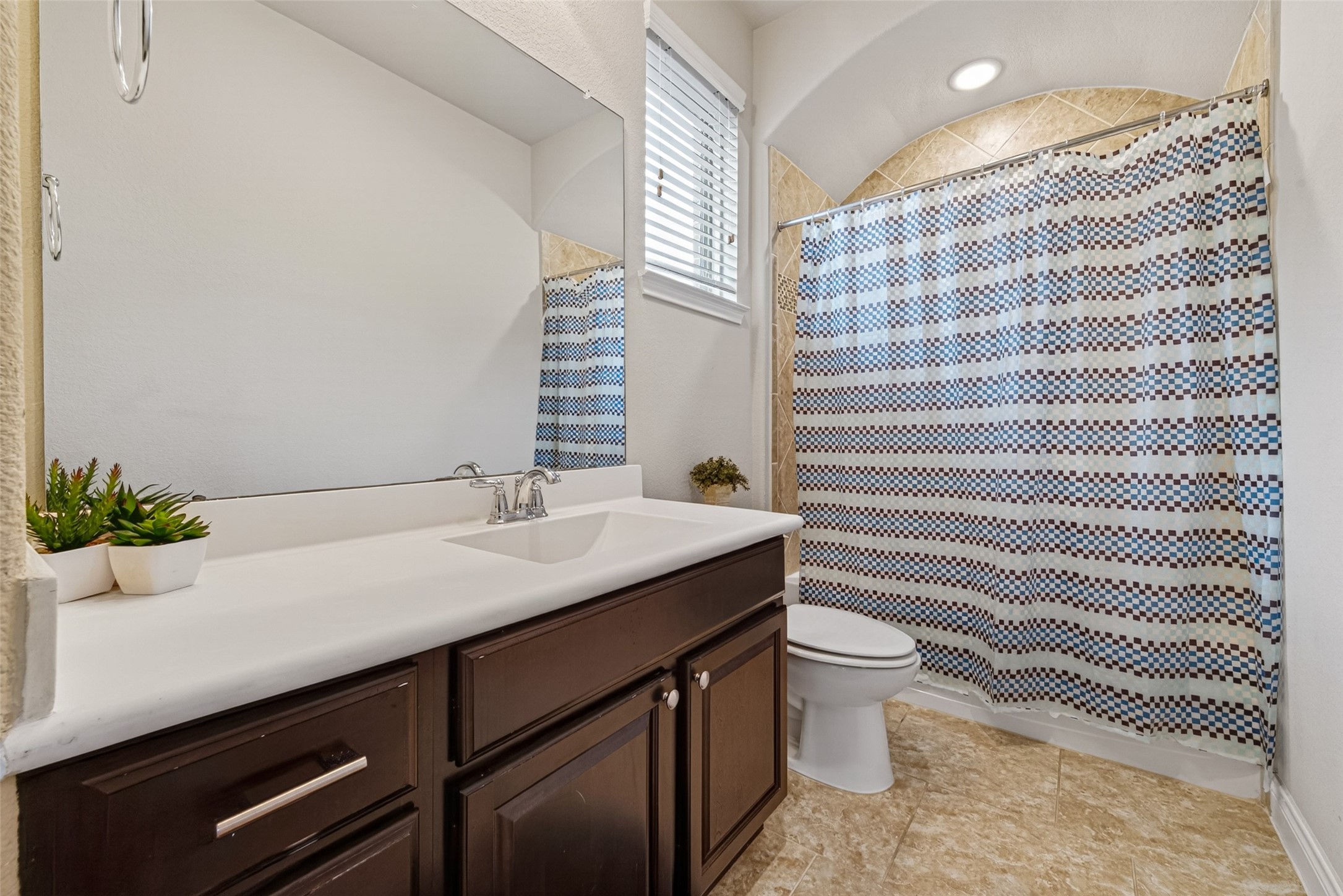 25611 Ellis Ridge Court Katy, TX 77494 - Photo 39 of 49 Bright and inviting bathroom featuring a large mirror, modern sink with dark wood cabinetry, and a shower-tub combo with a decorative curtain. Neutral tile flooring and a small window add to the charm.