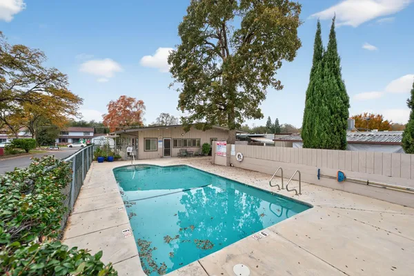 a view of a white house next to a yard with potted plants