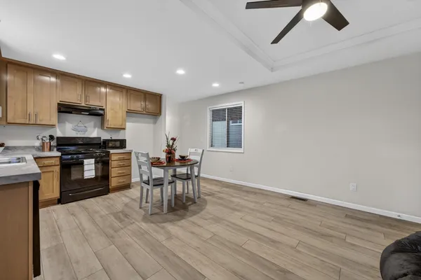 a kitchen with stainless steel appliances kitchen island hardwood floor sink stove dining table and chairs