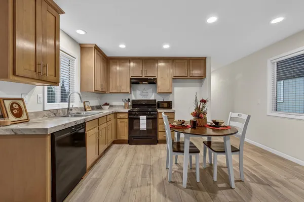a kitchen with stainless steel appliances granite countertop a stove a sink a microwave a dining table and chairs