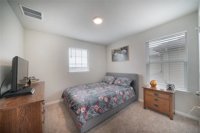 a bedroom with a bed and a flat tv screen on a dresser