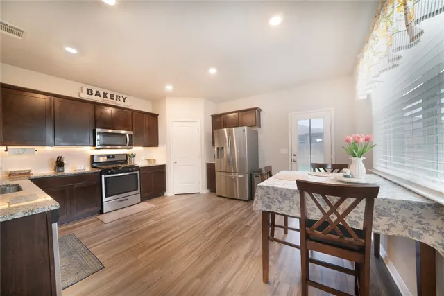 a kitchen with stainless steel appliances kitchen island granite countertop a table chairs stove and refrigerator