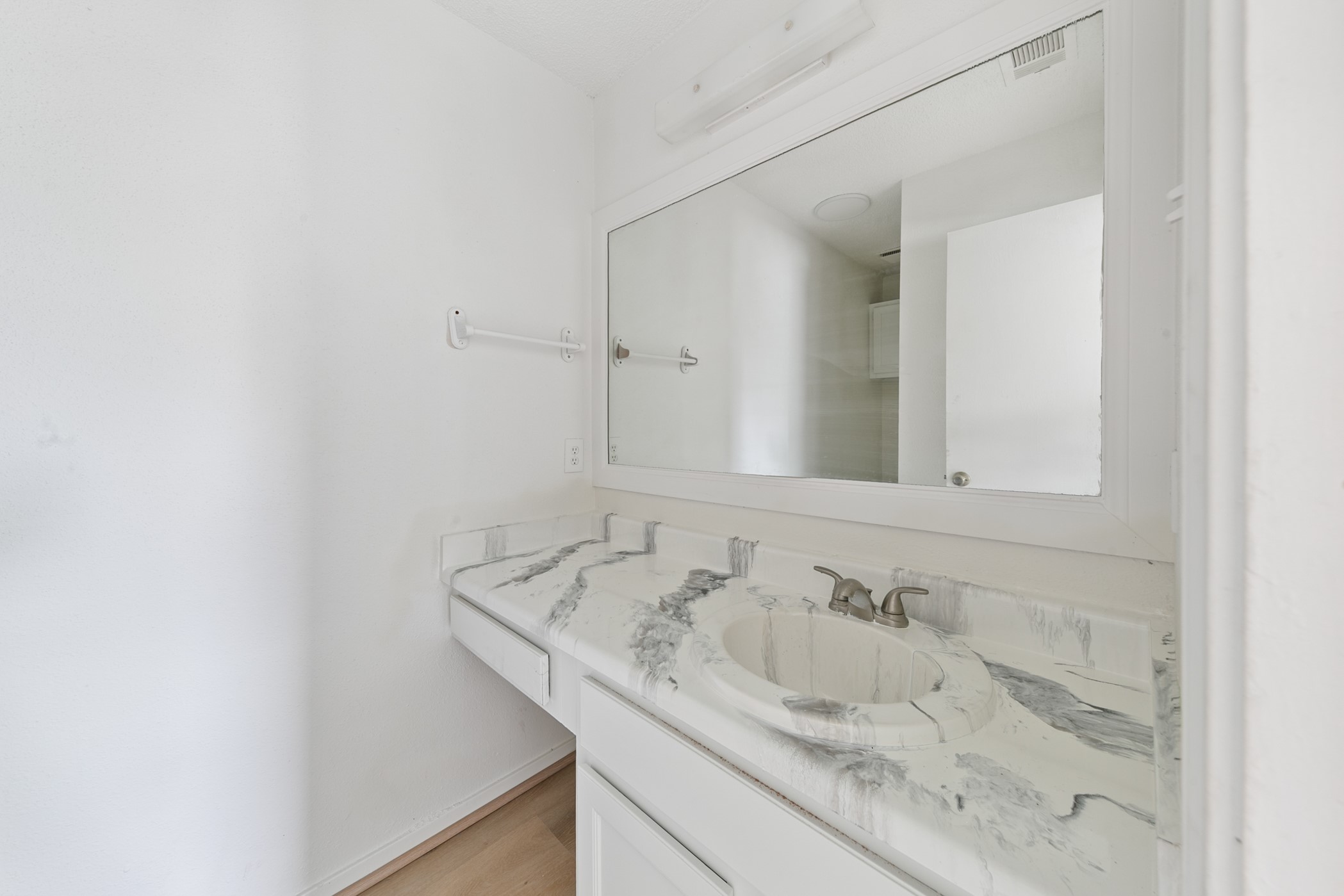 700 Lyle W Avenue, Unit D Cleveland, TX 77327 - Photo 15 of 16 This bathroom features a sleek design with a large mirror and a marbled countertop. The space is minimalistic and bright, offering a clean and modern look.