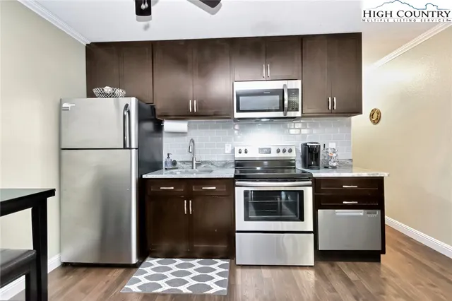 a kitchen with stainless steel appliances granite countertop a refrigerator a stove a sink and a microwave