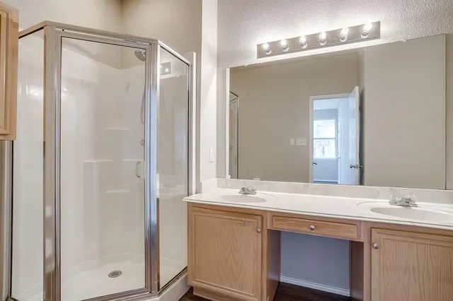 a bathroom with a double vanity sink mirror and shower