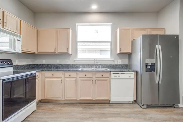 a kitchen with granite countertop cabinets stainless steel appliances a sink and a window
