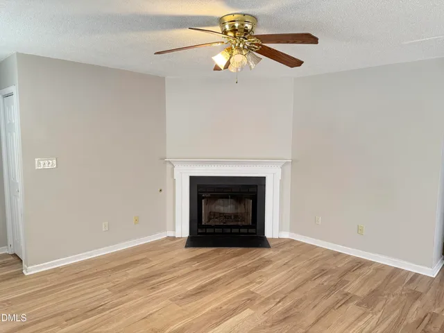 an empty room with a fireplace and wooden floor